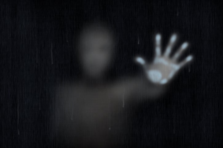 spooky illustration of a ghost with hand pressed on a glass window and a blurred body
